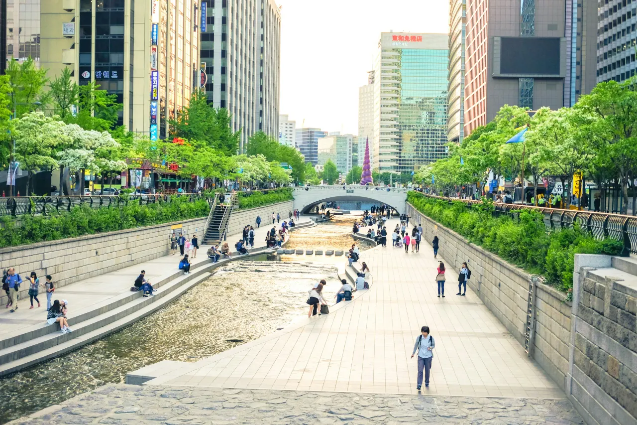 낮에 고층 건물 근처의 보도를 걷는 사람들